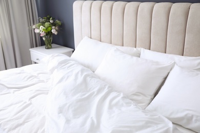 Photo of Comfortable bed with soft pillows indoors, closeup