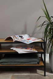 Wooden cabinet with magazines near houseplant indoors