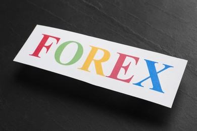 Sheet of paper with word Forex on black table, closeup