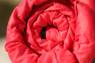 Red sleeping bag on blurred background, closeup. Camping equipment