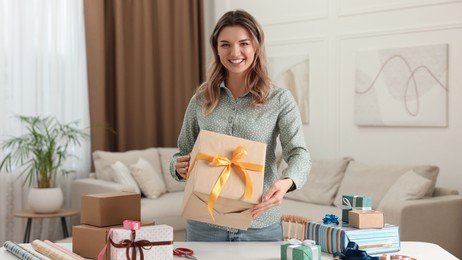 Young woman with beautifully wrapped gifts in living room