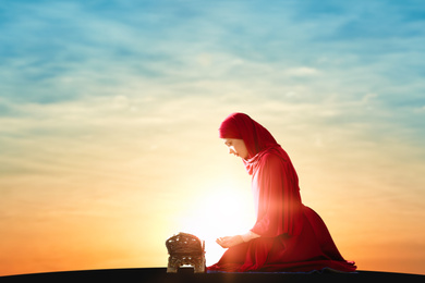 Muslim woman in traditional clothes praying at sunrise. Holy month of Ramadan