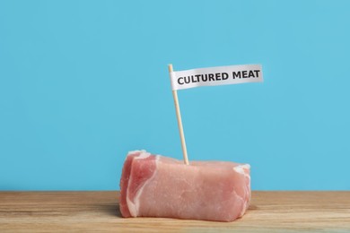 Sample of lab grown pork labeled Cultured Meat on wooden table
