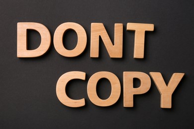 Photo of Words Don't Copy made of wooden letters on black background, flat lay. Plagiarism concept