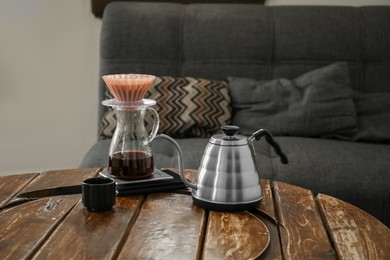 Jug of coffee with wave dripper and kettle on wooden table in cafe