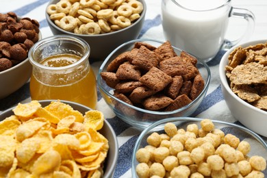 Different delicious breakfast cereals, milk and honey on kitchen towel