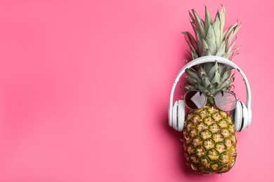 Top view of pineapple with headphones and sunglasses on pink background, space for text. Creative concept