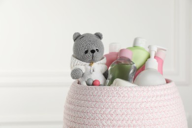 Basket full of different baby cosmetic products and toy on blurred background, closeup