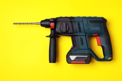 Modern electric power drill and different bits on yellow background, flat lay