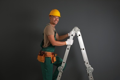 Professional constructor climbing ladder on black background