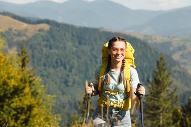 Woman with trekking poles hiking in mountains
