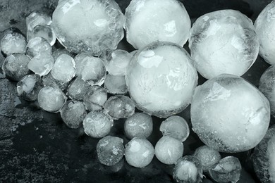 Many melting ice balls on black table, above view