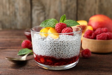 Delicious chia pudding with raspberries, peach and mint on wooden table