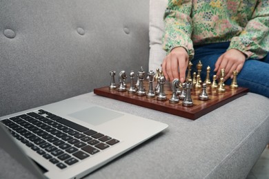 Woman playing chess with partner through online video chat on sofa, closeup