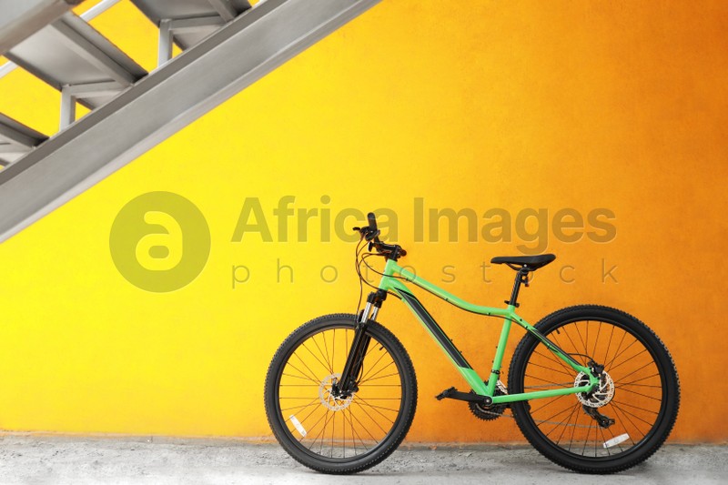 New modern color bicycle near yellow wall outdoors