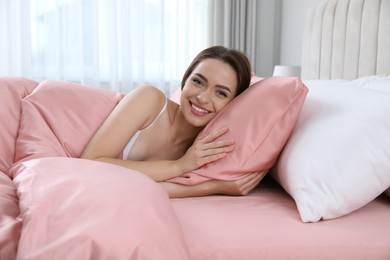 Young woman lying in comfortable bed with silky linens