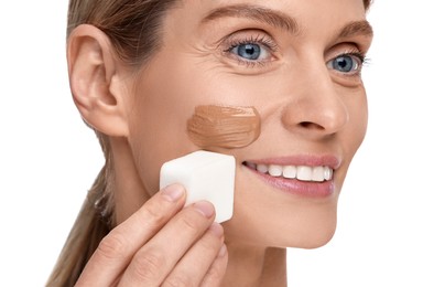 Photo of Woman applying foundation on face with makeup sponge against white background