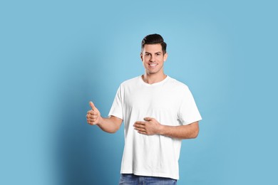 Happy healthy man touching his belly on light blue background