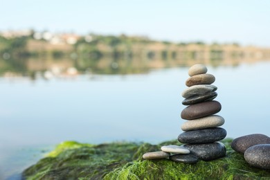 Stack of stones on seaweed near river, space for text. Harmony and balance concept