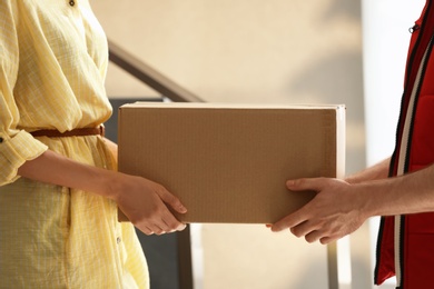 Woman receiving parcel from deliveryman on blurred background, closeup. Space for text