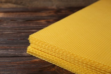 Photo of Natural beeswax sheets on wooden table, closeup. Space for text