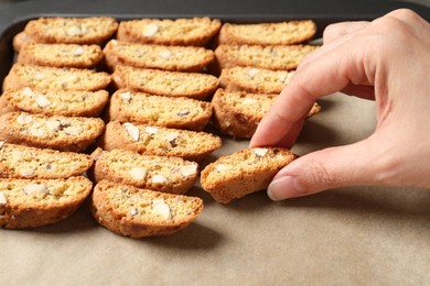 Woman taking traditional Italian almond biscuit (Cantucci) from baking sheet, closeup
