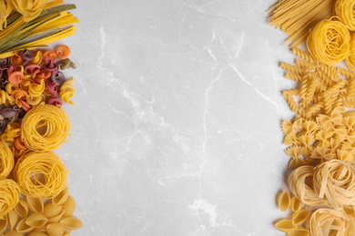 Different types of pasta on light grey marble table, flat lay. Space for text
