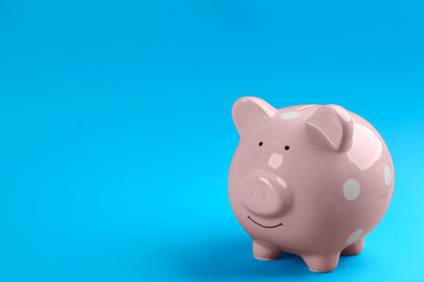 Pink piggy bank on blue background. Space for text