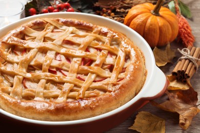 Delicious homemade apple pie and autumn decor on wooden table, closeup. Thanksgiving Day celebration