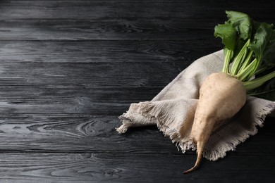 Photo of Fresh sugar beet with leaves on black wooden table. Space for text