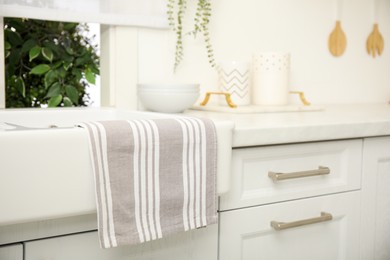 Clean towel hanging on white sink in kitchen