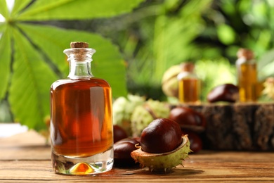 Chestnuts and bottle of essential oil on table against blurred background. Space for text