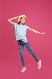 Full length portrait of preteen girl in hat on pink background