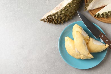 Plate with fresh ripe durian and knife on grey table, flat lay. Space for text