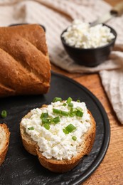 Photo of Bread with cottage cheese and green onion on wooden table, closeup