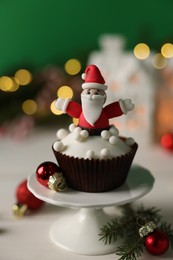 Photo of Tasty Christmas cupcake with Santa Claus figure on white table