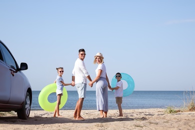 Family with inflatable rings near car at beach