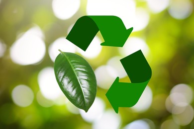 Recycling symbol made of arrows and green leaf on blurred background. Bokeh effect