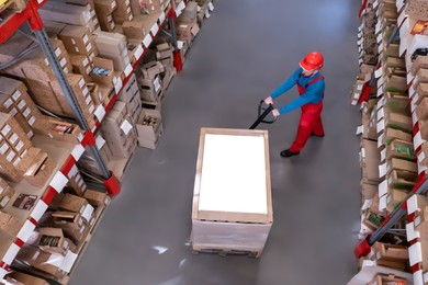Man in hardhat working with pallet truck at warehouse, above view. Logistics center