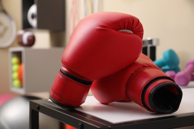 Red boxing gloves on white table in room with other sports equipment
