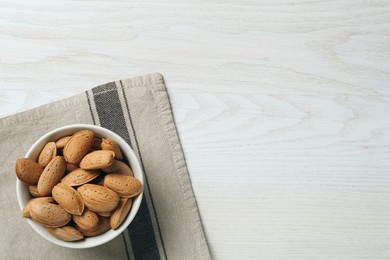 Ceramic bowl with almonds on white wooden table, top view and space for text. Cooking utensil