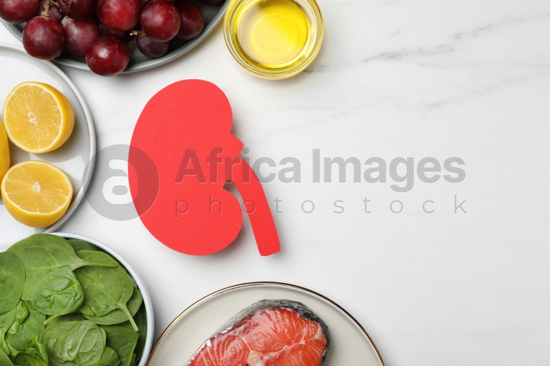 Photo of Flat lay composition with paper cutout of kidney and different products on white marble table, space for text