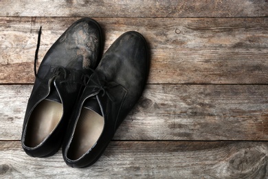 Dirty shoes and space for text on wooden background, top view. Poverty concept