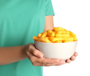 Woman holding bowl of crunchy cheesy corn sticks on white background, closeup