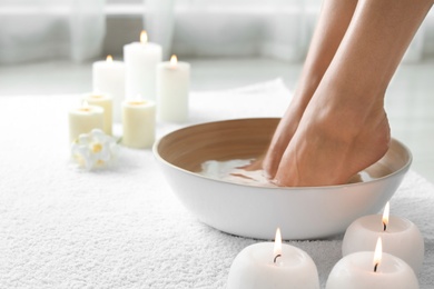Woman soaking her feet in dish indoors, closeup with space for text. Spa treatment