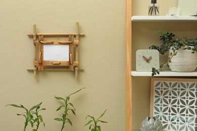 Decor elements on shelving unit near beige wall with bamboo frame indoors