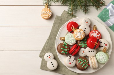 Beautifully decorated Christmas macarons and fir branches on white wooden table, flat lay. Space for text