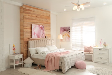Stylish bedroom interior with modern ceiling fan and pictures