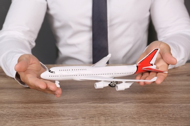 Insurance agent holding toy plane at table, closeup. Travel safety concept