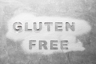 Words Gluten free written with flour on grey background, top view